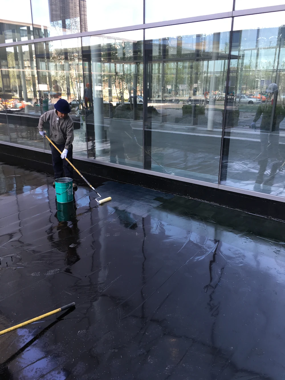 construction worker rolling waterproofing membrane outside of a building