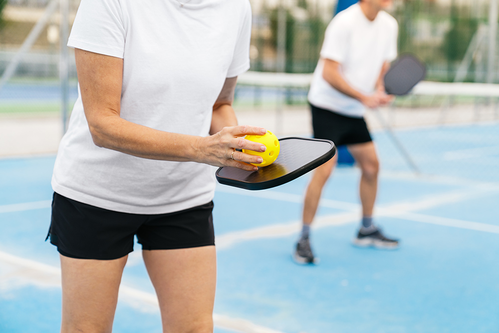 Two pickleball players on an outdoor court.