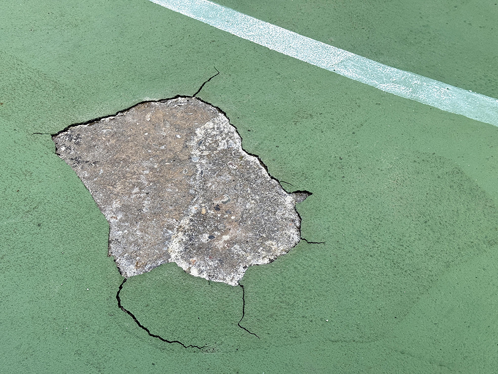 Damaged basketball or tennis court surface.