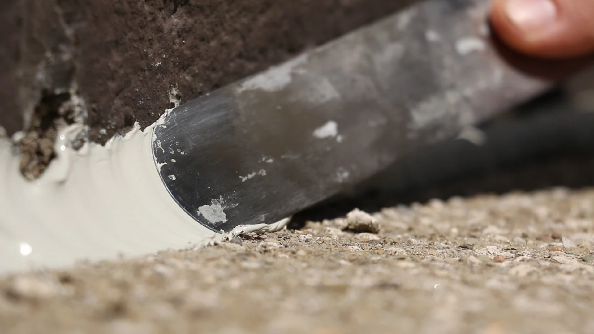 Concrete sealant application with a spatula.