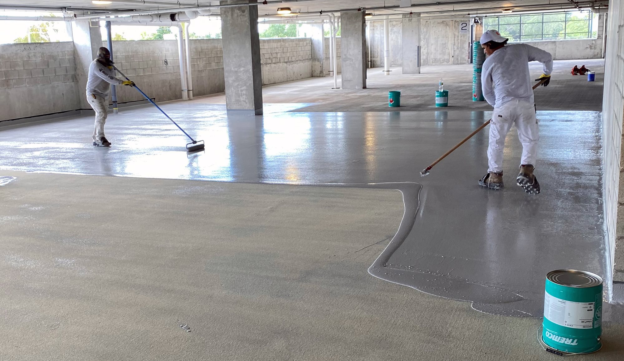 Workers applying deck coating to parking garage.