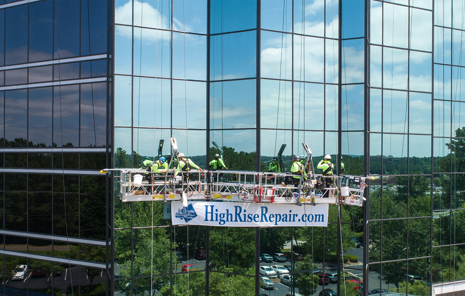 Glass building with workers on a swing stage.
