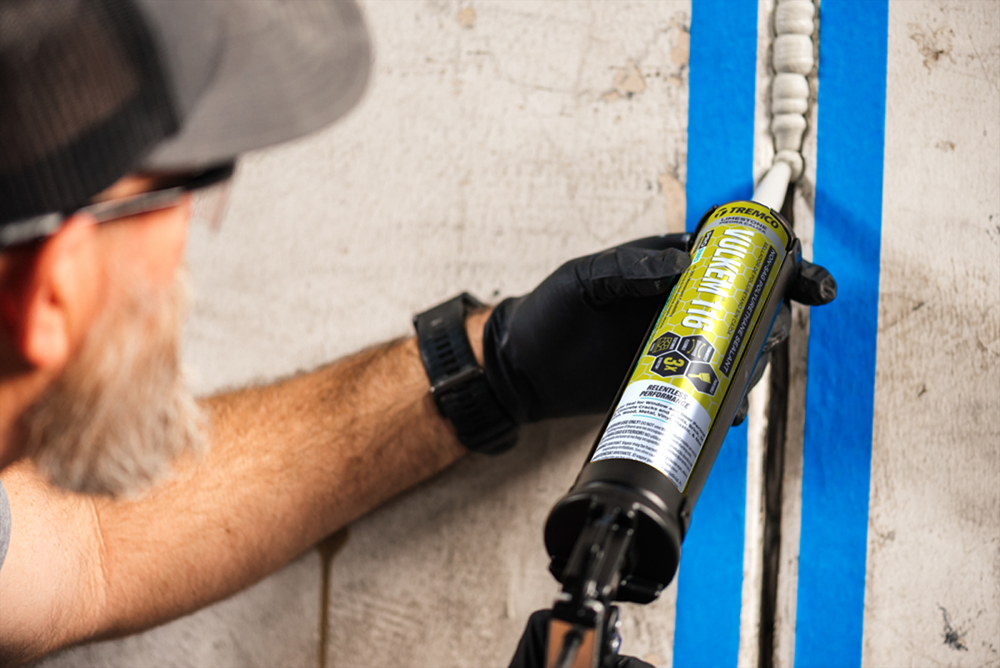 Construction worker installing concrete sealant.