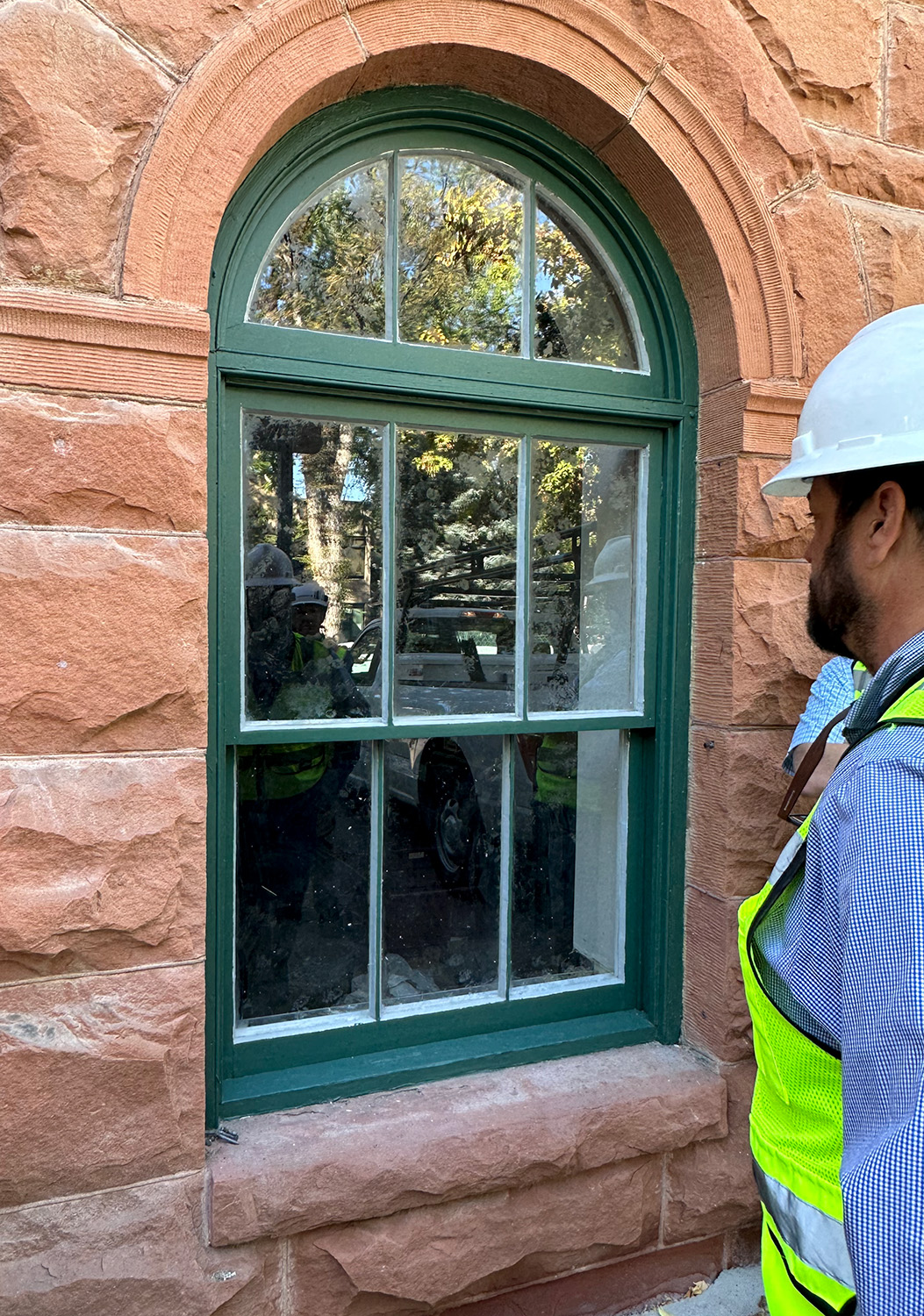 Construction worker looking at sealant  on a stone masonry joint.